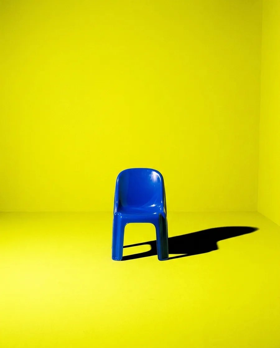 A single blue chair on a yellow floor